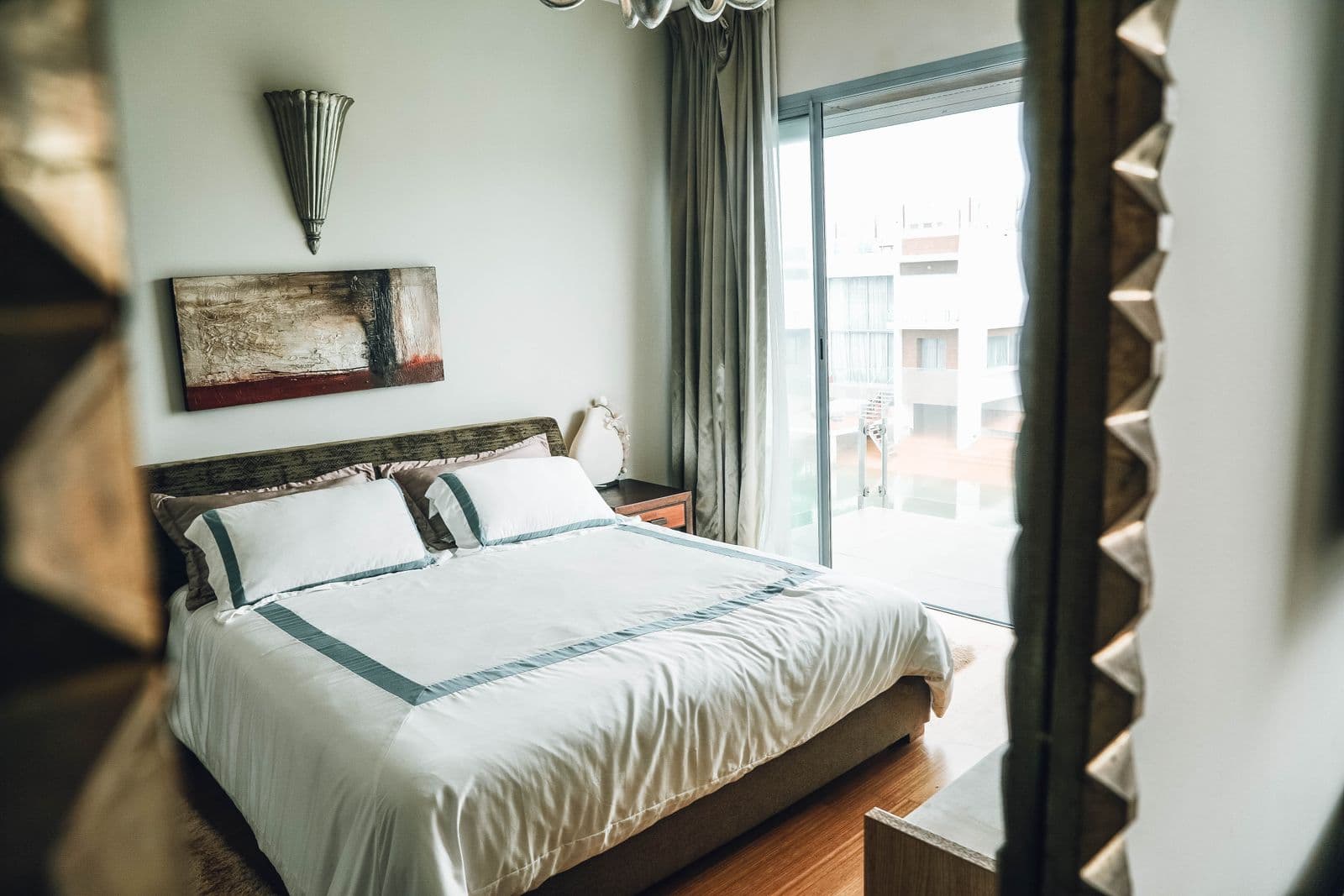 A bright, tidy modern bedroom with natural light through a large window.